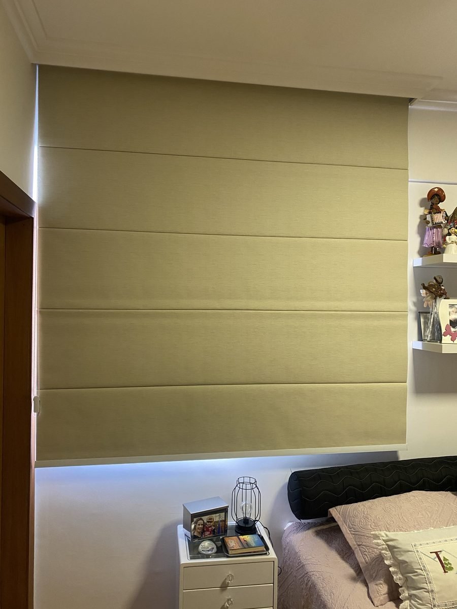 Quarto com cortina romana bege fechada ao lado da cama