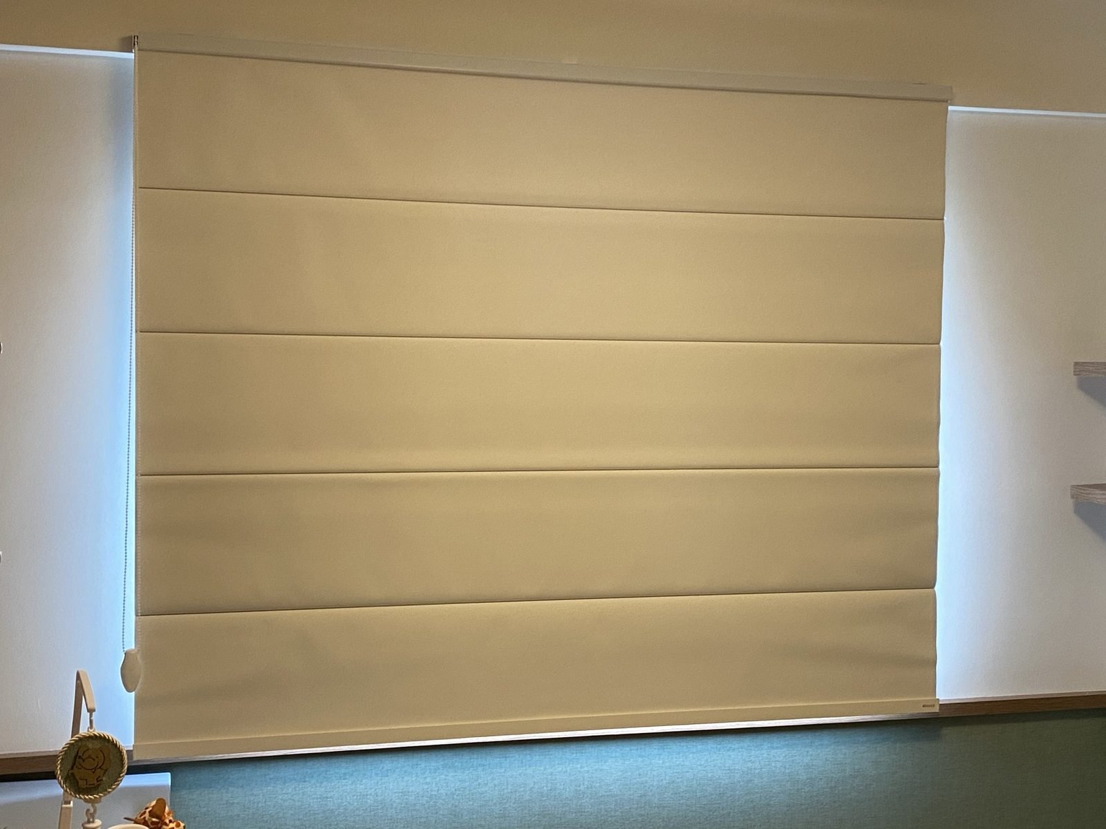 Cortina romana bege em pano largo instalada em sala de estar