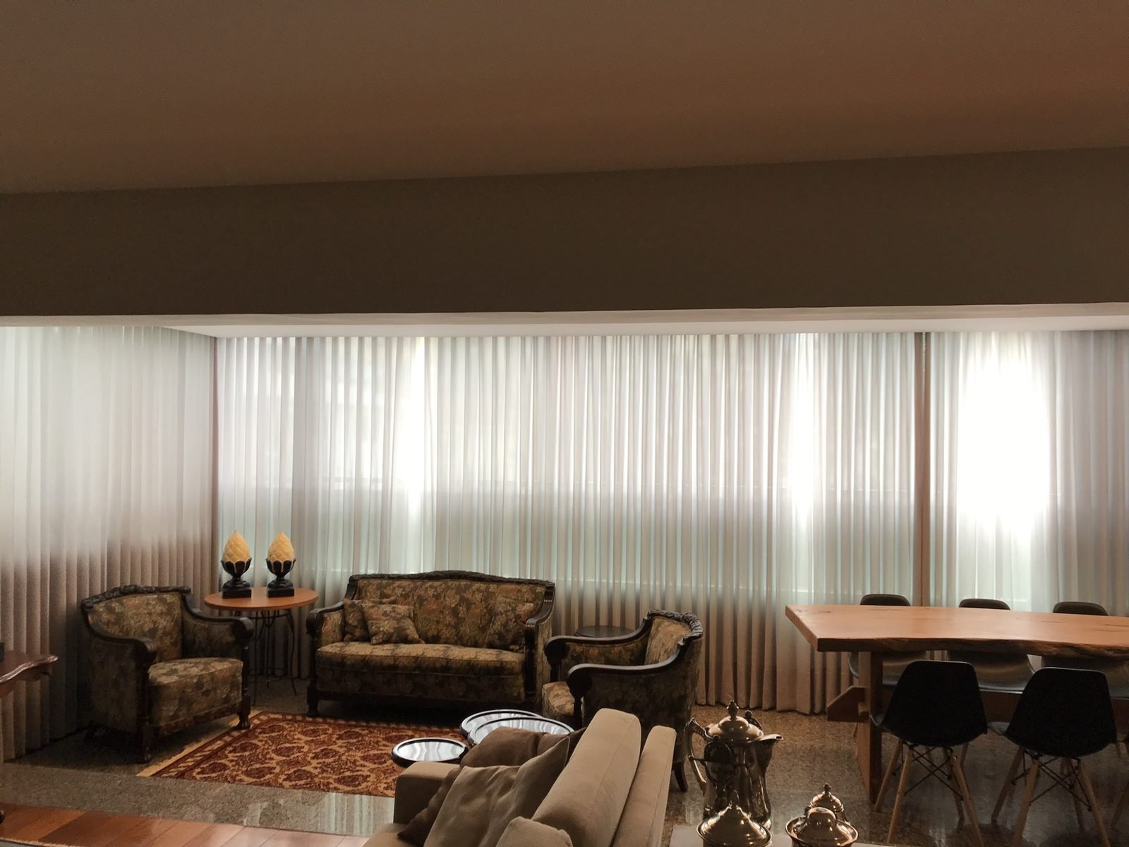 Sala de estar clássica com cortinas wave claras em toda a parede de janelas